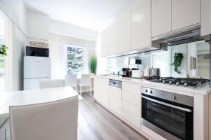 a white kitchen with white cabinets and appliances at Snug 1-Bed Unit Across from Bondi Beach in Sydney