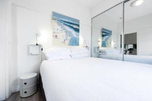a bedroom with a large white bed and a mirror at Snug 1-Bed Unit Across from Bondi Beach in Sydney