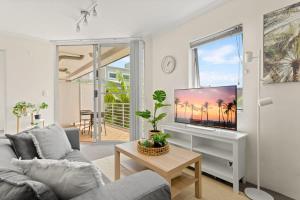 een woonkamer met een bank en een tv bij Charming 1-Bed Apartment Close to Shops and Parks in Sydney