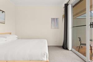 een slaapkamer met een bed en een glazen schuifdeur bij Charming 1-Bed Apartment Close to Shops and Parks in Sydney