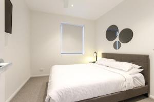 a bedroom with a white bed with mirrors on the wall at Gorgeous 2-Bed Apartment By Shops and the River in Batemans Bay