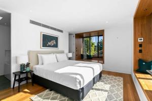 a bedroom with a large white bed with a rug at Impeccable 3-Bed Home Near the Beach in Sydney