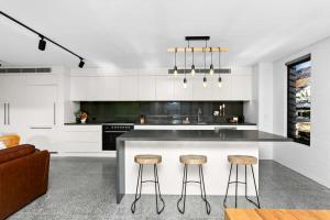 a kitchen with a large island with stools at Impeccable 3-Bed Home Near the Beach in Sydney