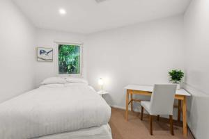 a bedroom with a bed and a desk and a table at Leafy Retreat with Deck & City Convenience in Sydney