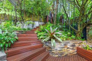 una pasarela de madera en un jardín con plantas en Leafy Retreat with Deck & City Convenience, en Sídney