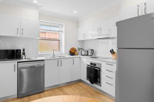 a kitchen with white cabinets and a refrigerator at Chic 2-Bed Unit Fully Renovated in Prime Location in Sydney