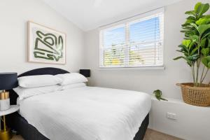 a bedroom with a white bed and a potted plant at Chic 2-Bed Unit Fully Renovated in Prime Location in Sydney