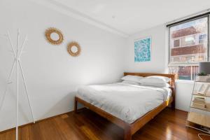 een witte slaapkamer met een bed en een raam bij Beautiful Boho 3-Bed by the Beach & the Bush in Sydney