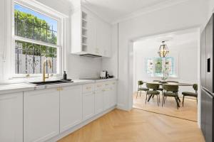 een keuken met witte kasten en een tafel met stoelen bij Superb 3-Bed Victorian Terrace by Darling Harbour in Sydney