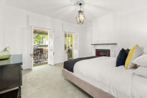 een witte slaapkamer met een groot bed en een open haard bij Superb 3-Bed Victorian Terrace by Darling Harbour in Sydney
