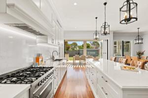 a kitchen with white counters and a stove top oven at Impeccably Chic 4-Bed Home with Spa & Pool in Sydney