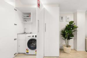 a white laundry room with a washer and dryer at Chic 2-Bed Unit Fully Renovated in Prime Location in Sydney