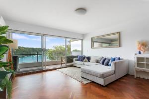 sala de estar con sofá blanco y ventanas grandes en Stunning double-story waterfront retreat, en Sídney