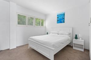 1 dormitorio blanco con 1 cama y 2 ventanas en Stunning double-story waterfront retreat, en Sídney