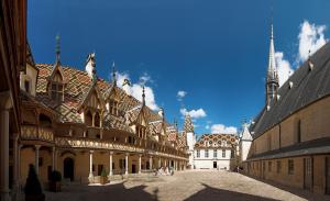 a courtyard of a building with a clock tower at Le Cara Caliel 2G in Beaune
