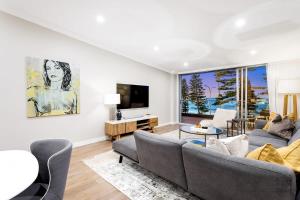 a living room with a couch and a tv at Glorious Beachfront 3-Bed with Breathtaking Views in Deewhy