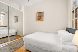 a white room with a bed and a mirror at Quaint 3-Bed Heritage Home in the Heart of Sydney in Sydney