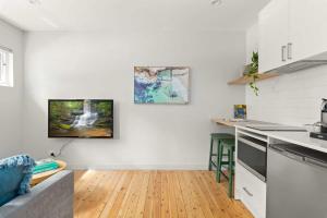 uma cozinha com paredes brancas e piso em madeira em Modern 1-Bed Pad Minutes Away from Coogee Beach em Sidney