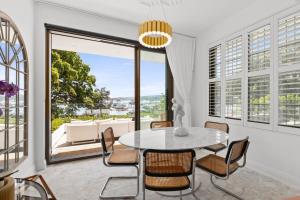 a dining room with a table and chairs and a large window at Superb 2-Bed Apartment Facing Rose Bay Marina in Sydney