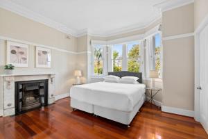 a white bedroom with a bed and a fireplace at Huge Harbour View Apartment In Historic Home in Sydney