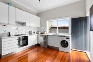 een keuken met witte kasten en een wasmachine en droger bij Huge Harbour View Apartment In Historic Home in Sydney