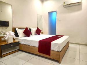 a bedroom with a bed with red and white pillows at Hotel Near Me in Rajkot