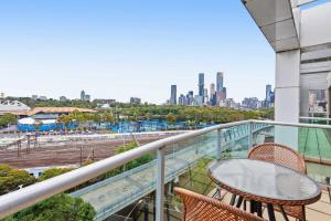 balcón con mesa, sillas y vistas a la ciudad en Spacious 3-Bed Apartment by the MCG en Melbourne