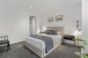 a white bedroom with a large bed and a desk at Stylish and Spacious 2-Bed Apartment Melbourne in Melbourne