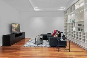a living room with a couch and a television at Stylish and Spacious 2-Bed Apartment Melbourne in Melbourne