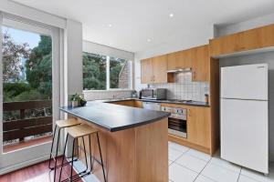 a kitchen with wooden cabinets and a large window at Central City Convenience in Prime Location in Melbourne