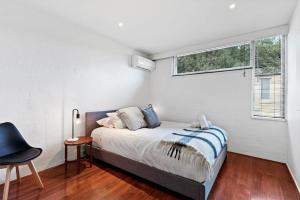 a white bedroom with a bed and a window at Central City Convenience in Prime Location in Melbourne