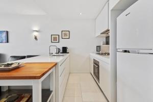 a kitchen with white cabinets and a wooden table at Beautiful 1-Bed Unit in The Heart of Melbourne in Melbourne