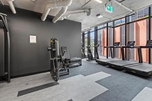a gym with rows of tread machines and windows at Executive 2-Bed Apartment with Views, Gym and Pool in Melbourne