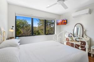 a white bedroom with a bed and a window at Delightful 2-Bed Townhouse Close to the Beach in Frankston