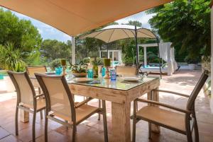 uma mesa com cadeiras e um guarda-sol num pátio em Villa Claudia - Ibiza em Sant Rafael de Sa Creu