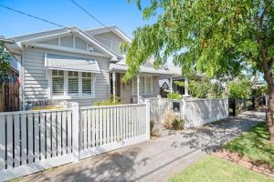 a white fence in front of a house at Sophisticated 2-Bed House with a Pool in Seddon