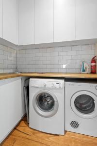 a washer and dryer in a kitchen with white cabinets at Sophisticated 2-Bed House with a Pool in Seddon