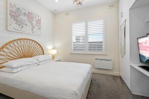 a white bedroom with a bed and a television at Sophisticated 2-Bed House with a Pool in Seddon