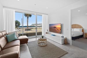 ein Wohnzimmer mit einem Sofa und einem großen Fenster in der Unterkunft Bespoke 2-Bed Beachfront Apartment in Melbourne