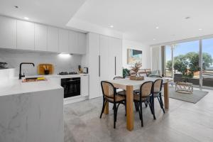eine Küche und ein Esszimmer mit einem Tisch und Stühlen in der Unterkunft Bespoke 2-Bed Beachfront Apartment in Melbourne