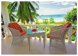 einen Tisch und Stühle auf einem Balkon mit Meerblick in der Unterkunft Rosemary's Guesthouse in Praslin
