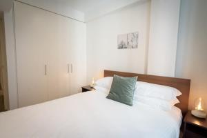 a bedroom with a white bed with a green pillow at Modern 2-Bed Apartment in Melbourne's Heart in Melbourne