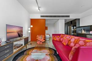 a living room with a red couch and a glass table at Vibrant 2-Bed Apartment Near St Kilda Beach in Melbourne