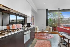a kitchen with a stove and a table with chairs at Vibrant 2-Bed Apartment Near St Kilda Beach in Melbourne