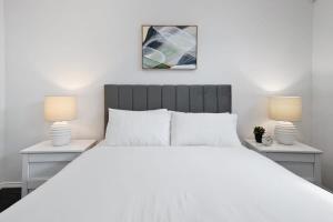 メルボルンにあるSleek 2-Bed Terrace near Local Parksのベッドルーム(白い大型ベッド、ランプ2つ付)
