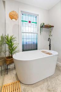 a white bath tub in a bathroom with a window at Refined 2-Bed House with a Charming Courtyard in Melbourne
