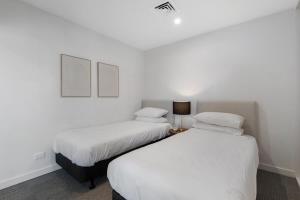 2 łóżka w pokoju z białymi ścianami w obiekcie Elegant 2-Bed with Large Balcony by High Street w Melbourne