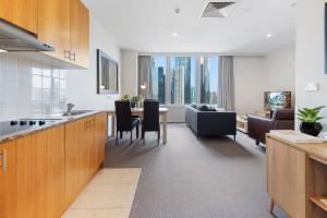 eine Küche und ein Wohnzimmer mit einem Sofa und einem Tisch in der Unterkunft Unbeatable 2-Bed Apartment In City Centre in Melbourne