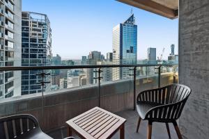 a balcony with a chair and a table and a view at Chic Central Pad with City Views, Pool and Gym in Melbourne