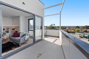 an empty living room with a chair and large windows at Stylish and Convenient Two Bedroom Apartment in Burwood